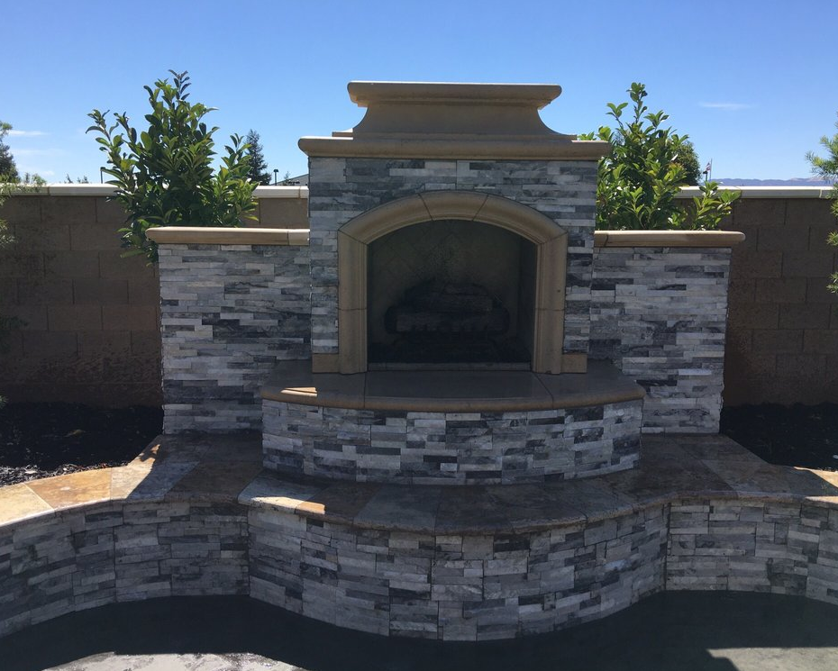 a picture of a stacked stone fireplace with a stamped concrete patio and sitting area in Modesto, California